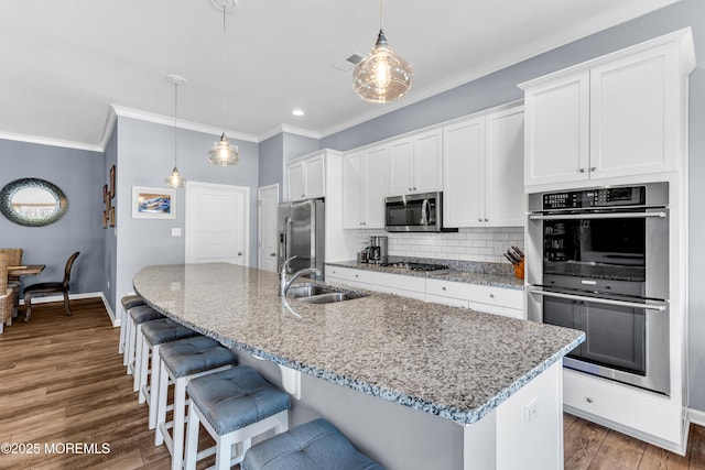 kitchen featuring sink, stainless steel appliances, a kitchen island with sink, and hanging light fixtures