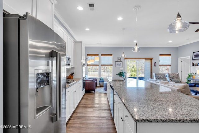 kitchen featuring white cabinets, dark stone counters, appliances with stainless steel finishes, and pendant lighting