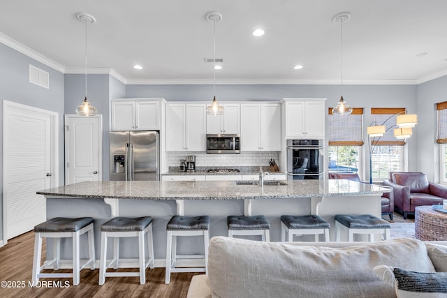 kitchen featuring appliances with stainless steel finishes, white cabinets, and decorative light fixtures