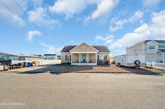 view of front facade with covered porch, a residential view, and fence