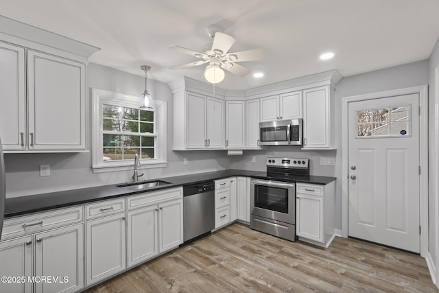 kitchen with stainless steel appliances, white cabinetry, sink, and ceiling fan