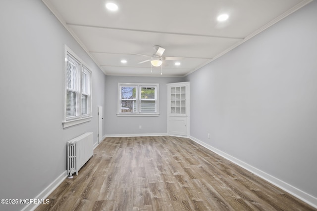 unfurnished room featuring crown molding, ceiling fan, light hardwood / wood-style flooring, and radiator heating unit