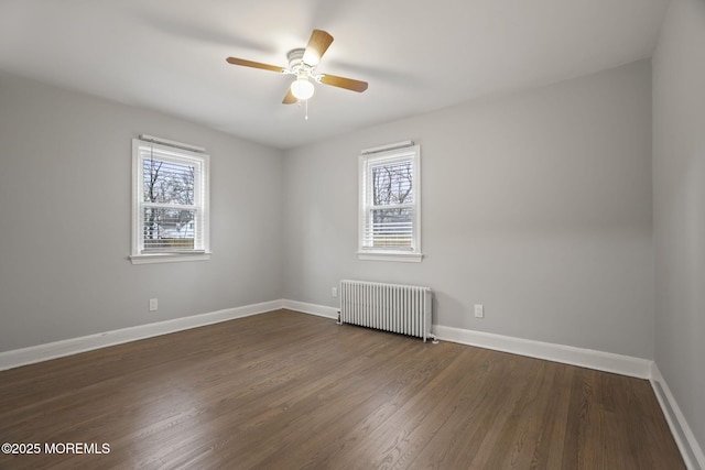 spare room featuring radiator, ceiling fan, and dark hardwood / wood-style floors