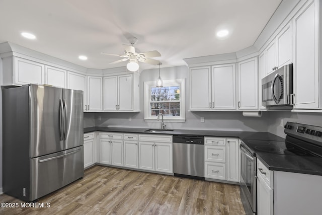 kitchen featuring stainless steel appliances, sink, white cabinetry, ceiling fan, and wood-type flooring