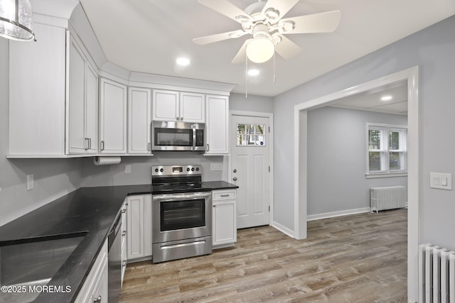 kitchen featuring stainless steel appliances, radiator, and white cabinetry