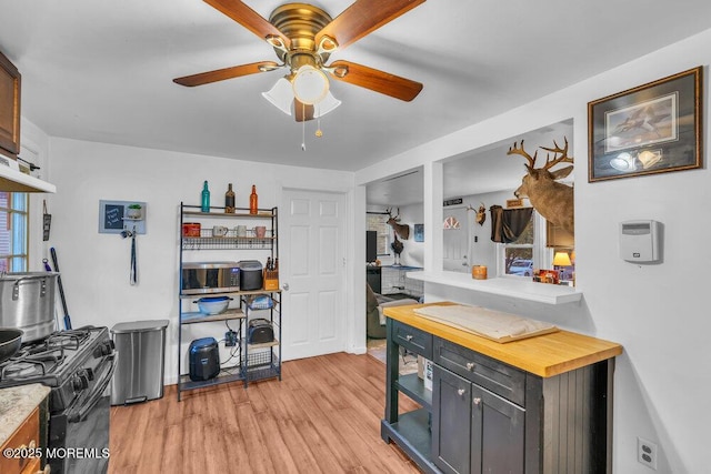 kitchen featuring black gas range oven, ceiling fan, dark brown cabinets, and light hardwood / wood-style flooring