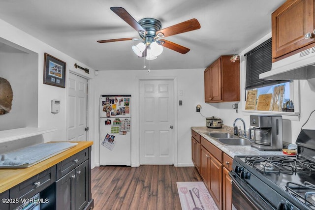 kitchen with sink, white fridge, black range with gas stovetop, ceiling fan, and dark hardwood / wood-style flooring