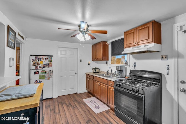 kitchen featuring black gas range, ceiling fan, refrigerator, dark hardwood / wood-style floors, and sink