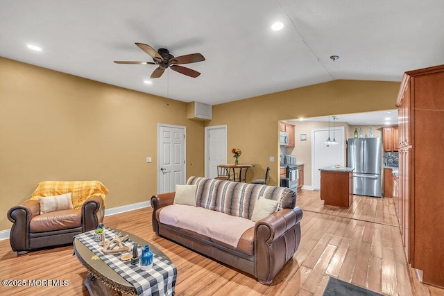 living room featuring ceiling fan, light hardwood / wood-style floors, and vaulted ceiling