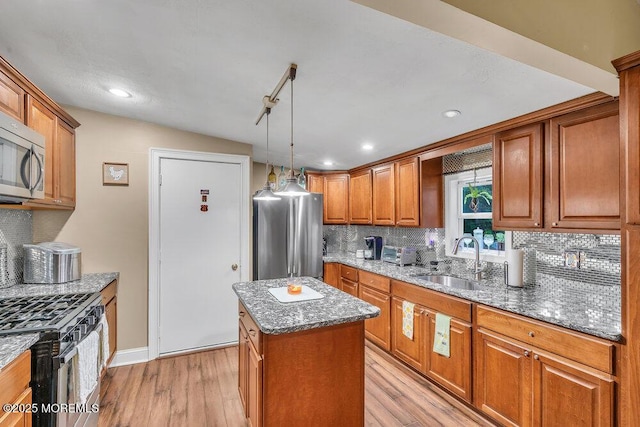 kitchen featuring a center island, stainless steel appliances, light wood-type flooring, stone countertops, and sink