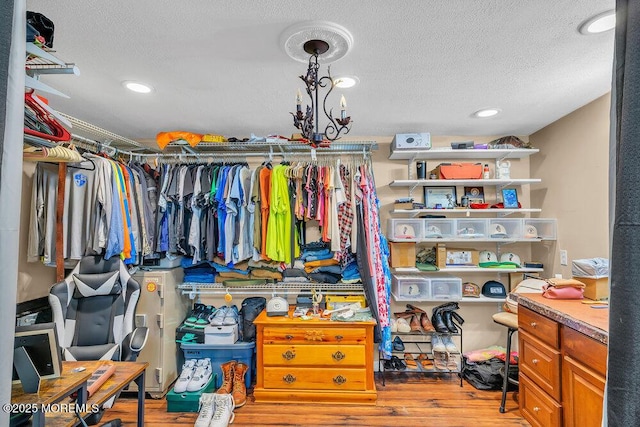 walk in closet featuring an inviting chandelier and light hardwood / wood-style floors