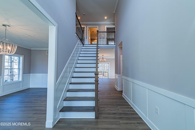 staircase featuring hardwood / wood-style floors, ornamental molding, and a chandelier