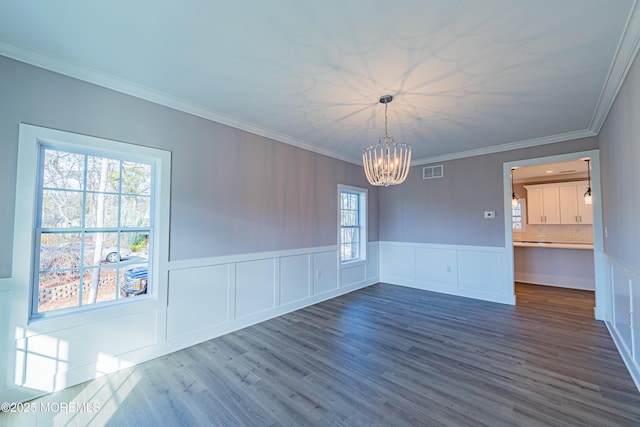 unfurnished dining area featuring dark hardwood / wood-style floors, ornamental molding, and a notable chandelier