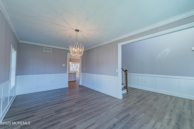 unfurnished room featuring crown molding, wood-type flooring, and a notable chandelier