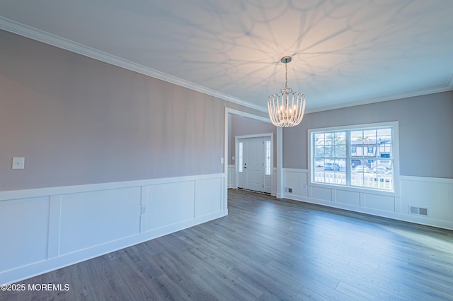 spare room featuring dark wood-type flooring, crown molding, and a chandelier