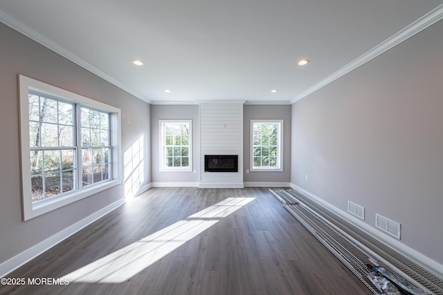 unfurnished living room featuring a healthy amount of sunlight, a large fireplace, and crown molding