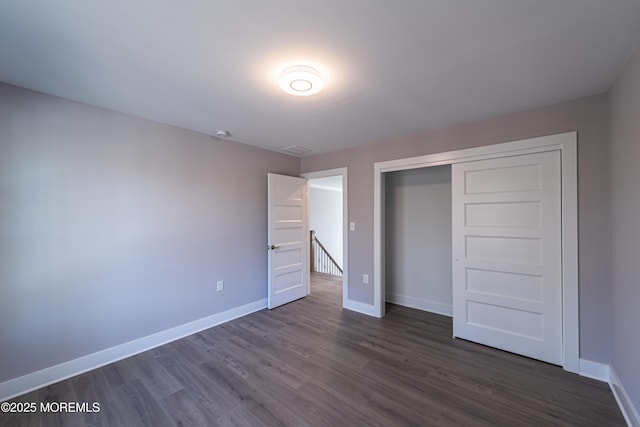 unfurnished bedroom with dark wood-type flooring and a closet