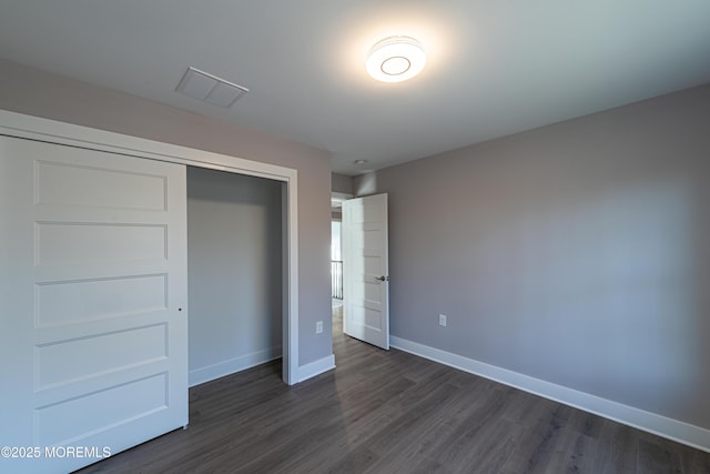 unfurnished bedroom with a closet and dark hardwood / wood-style floors