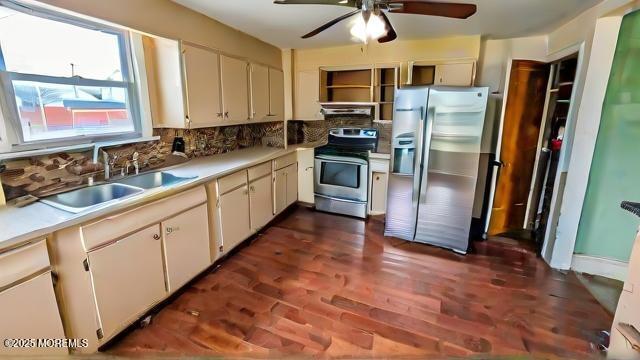 kitchen with range hood, decorative backsplash, white cabinetry, appliances with stainless steel finishes, and sink