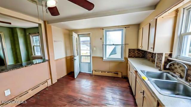 kitchen featuring sink, a baseboard heating unit, ceiling fan, and dark hardwood / wood-style floors