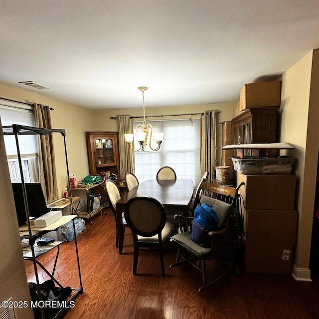 dining room with dark hardwood / wood-style flooring and a chandelier