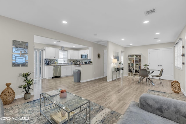 living room featuring sink and light hardwood / wood-style floors