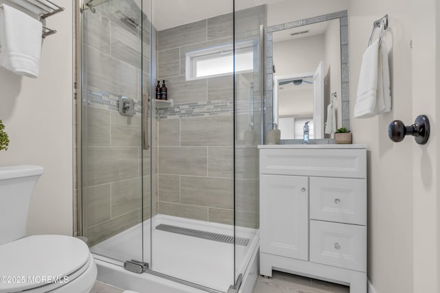 bathroom featuring vanity, toilet, and a shower with shower door