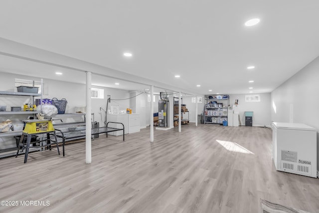 exercise area featuring washer / clothes dryer, gas water heater, and light hardwood / wood-style floors