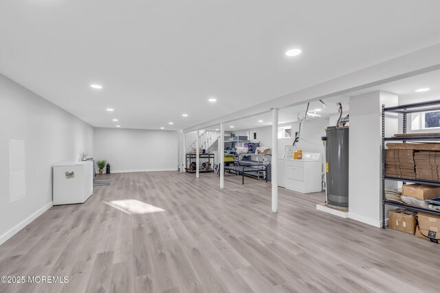 basement featuring water heater, washer / dryer, and light hardwood / wood-style floors