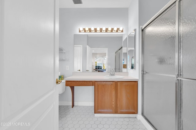 bathroom with a shower with door, vanity, and tile patterned flooring