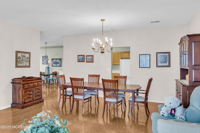 dining space with an inviting chandelier and light hardwood / wood-style flooring