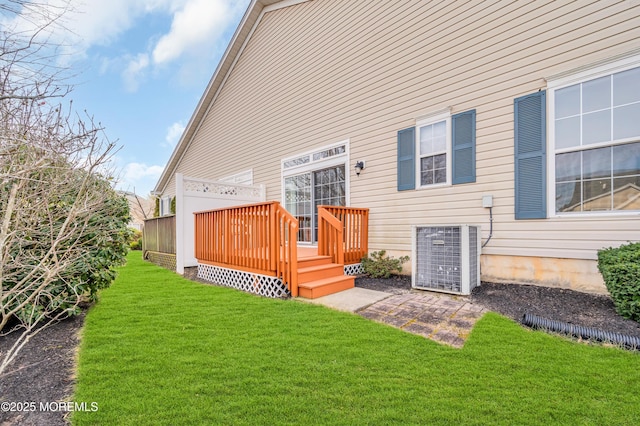 rear view of property featuring a lawn, central AC unit, and a wooden deck