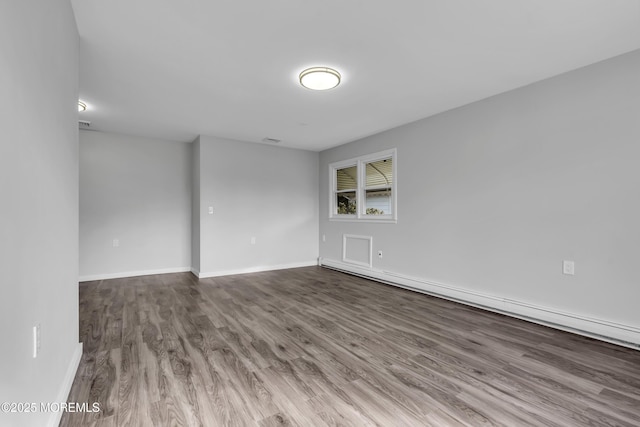 unfurnished room featuring baseboard heating and hardwood / wood-style flooring