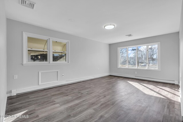 spare room featuring wood-type flooring and a baseboard heating unit