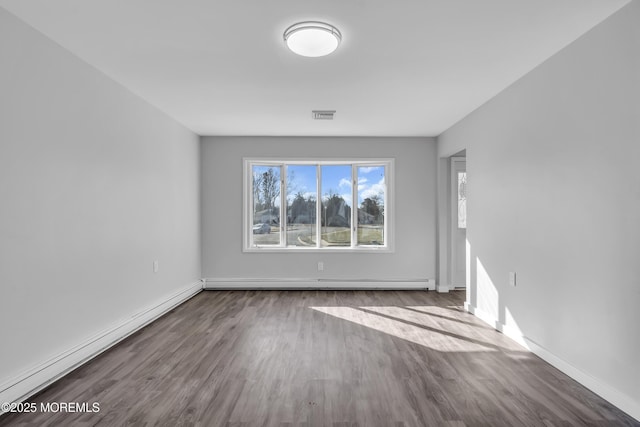 spare room with a baseboard heating unit and wood-type flooring