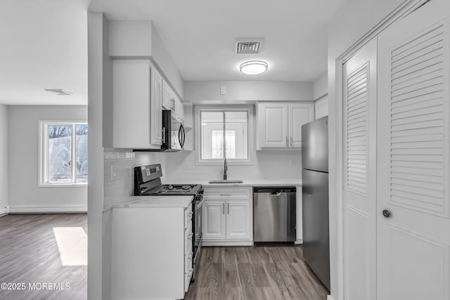 kitchen featuring sink, white cabinets, stainless steel appliances, and tasteful backsplash