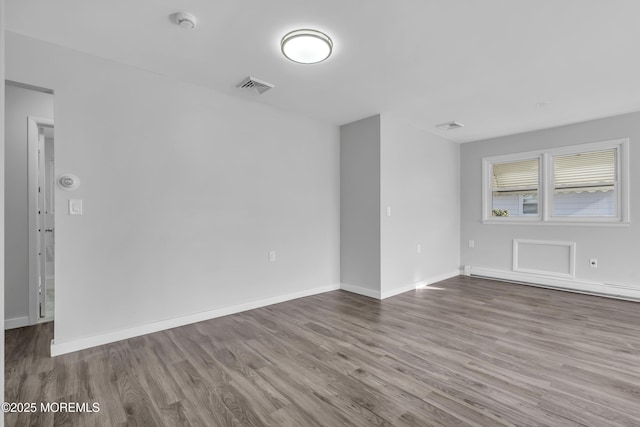 empty room with hardwood / wood-style flooring and a baseboard radiator