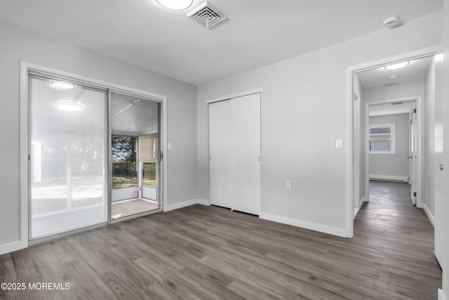 unfurnished bedroom featuring wood-type flooring, a closet, and access to outside