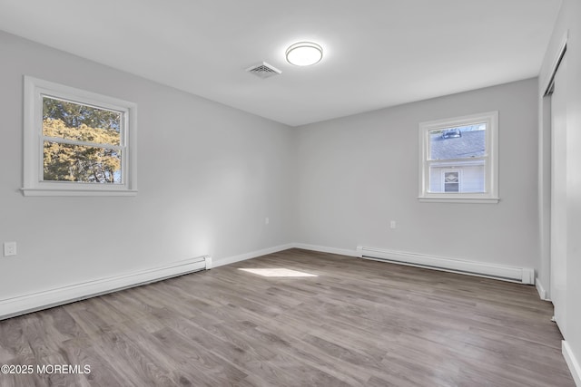 unfurnished room with a baseboard radiator, light hardwood / wood-style flooring, and a healthy amount of sunlight