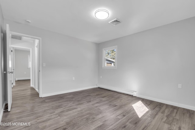 unfurnished room featuring hardwood / wood-style floors and a baseboard radiator