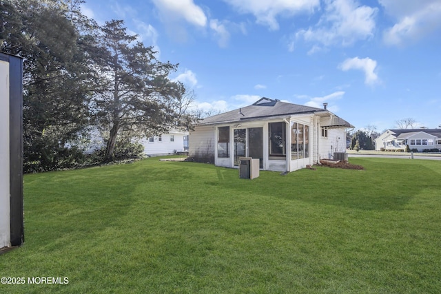 rear view of house featuring a sunroom, a yard, and central air condition unit