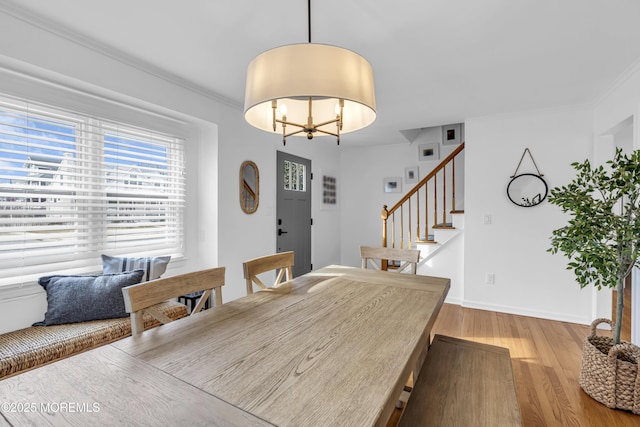 dining area featuring wood-type flooring, ornamental molding, and a notable chandelier