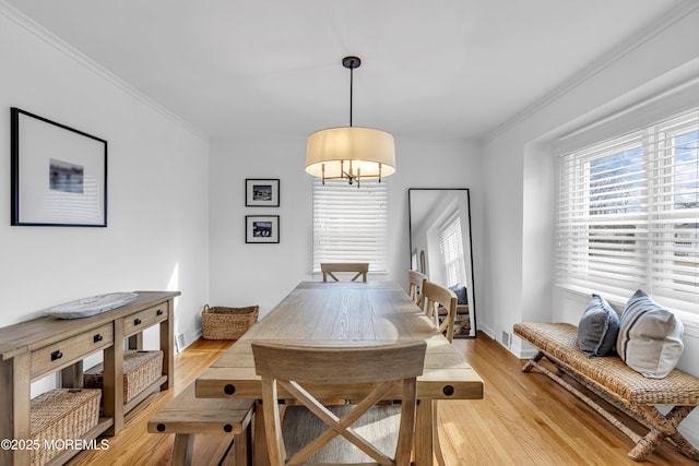 dining space featuring light wood-type flooring and crown molding