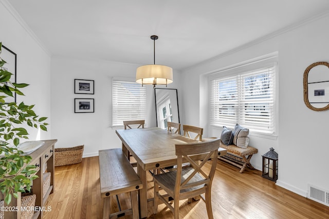 dining area featuring light wood-type flooring and crown molding