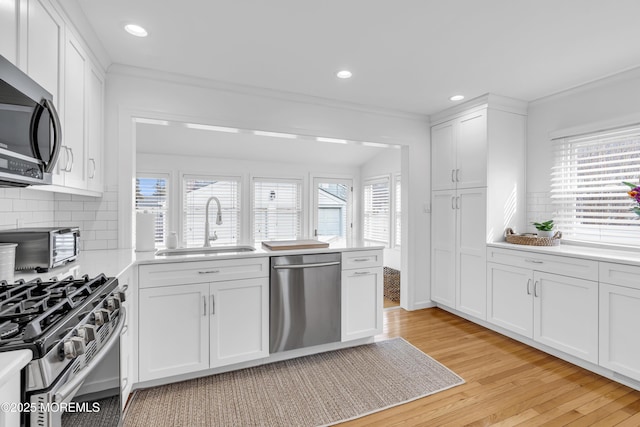 kitchen featuring backsplash, appliances with stainless steel finishes, sink, and white cabinetry