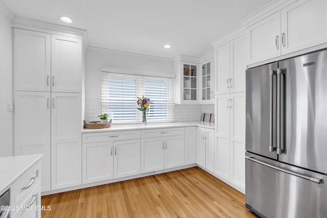 kitchen featuring light stone countertops, backsplash, white cabinets, and high quality fridge