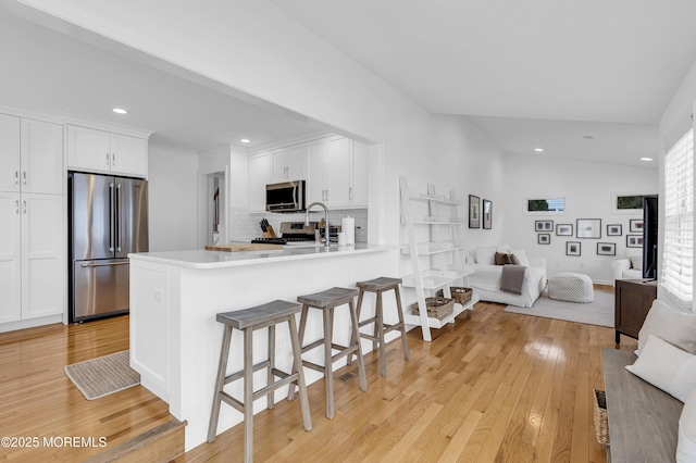 kitchen with white cabinetry, appliances with stainless steel finishes, kitchen peninsula, and tasteful backsplash