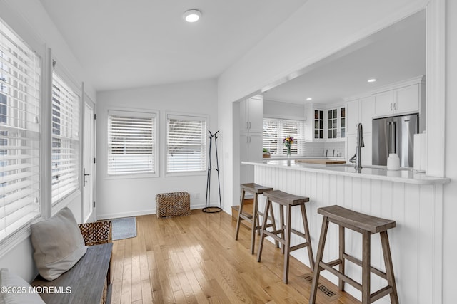 kitchen featuring backsplash, kitchen peninsula, white cabinetry, light hardwood / wood-style flooring, and high end fridge