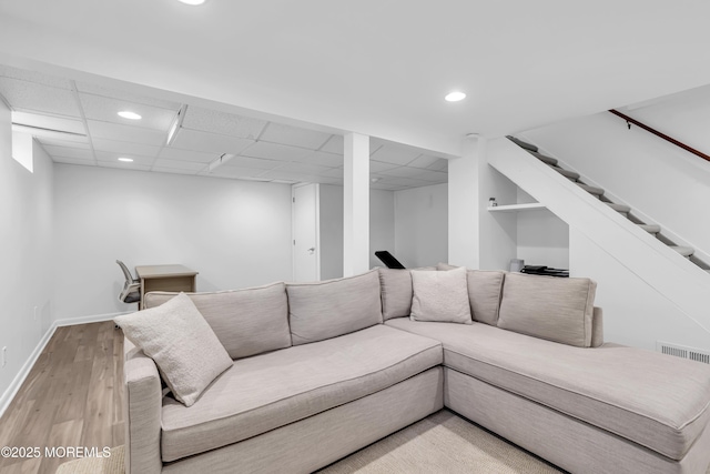 living room featuring light hardwood / wood-style flooring and a paneled ceiling