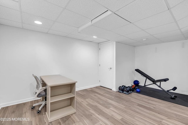 exercise area featuring a paneled ceiling and light hardwood / wood-style floors